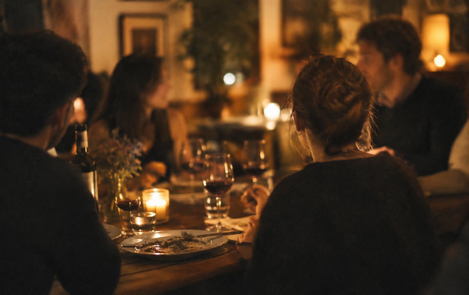 A small group sharing dinner by candlelight, illustrative photo